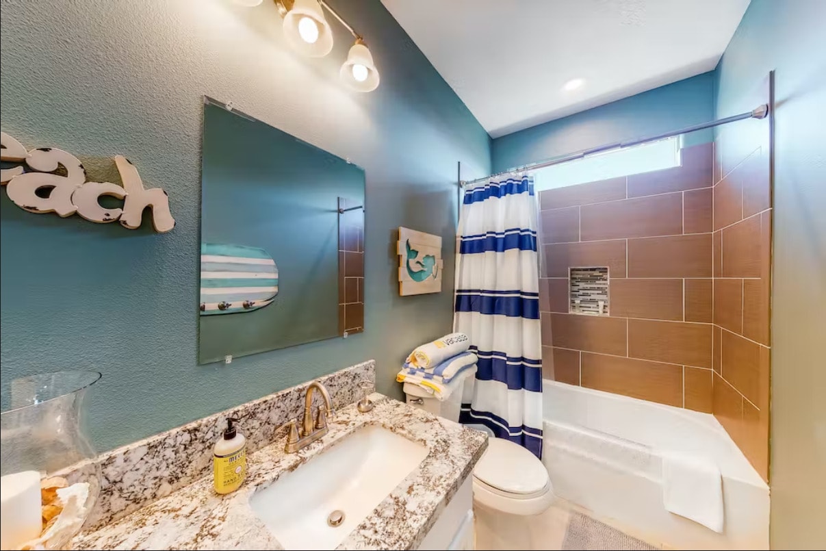 Coastal-themed guest bathroom with tub and granite countertop